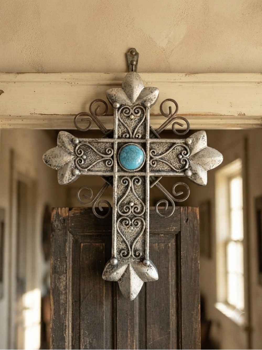 Silver-tone wall cross features a central turquoise stone and scrollwork detail